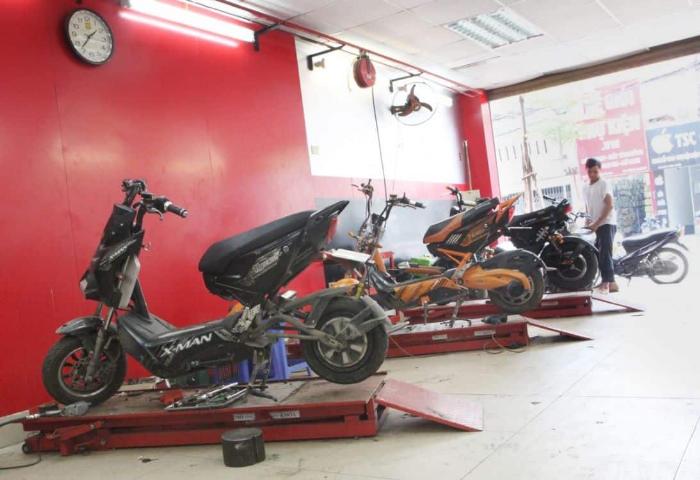 Hình ảnh một người đang cắm sạc cho xe đạp điện Xmen một cách cẩn thận trong garage